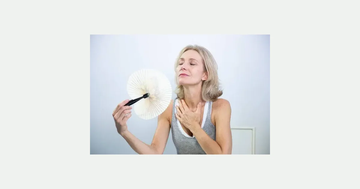 Woman using a handheld fan during a hot flush