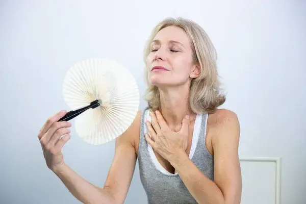 Woman fanning her face as she is flush